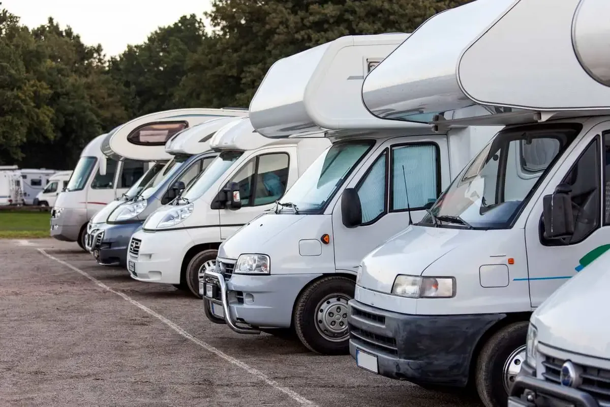 A row of white RVs parked at a campground.