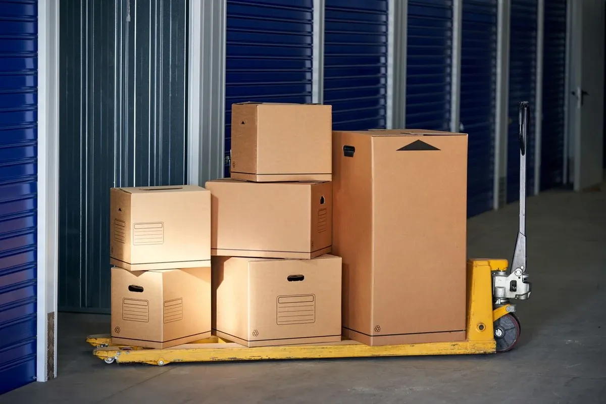 Stacks of multiple cardboard boxes on a trolley about to be stored in a self-storage unit.
